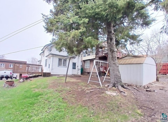rear view of house featuring a storage shed, a wooden deck, an outbuilding, and a lawn