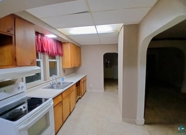 kitchen with electric stove, arched walkways, a sink, light countertops, and baseboards