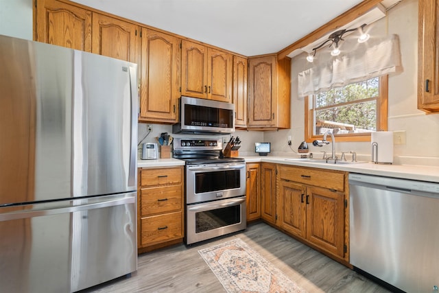 1741 Olsonville Crk, Carlton, MN 55718 - kitchen featuring stainless steel appliances, light countertops, a sink, brown cabinetry, and light wood-style flooring