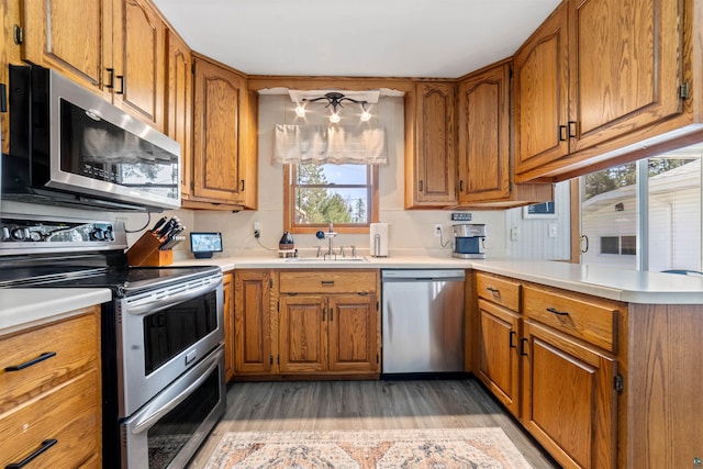 1741 Olsonville Crk, Carlton, MN 55718 - kitchen with stainless steel appliances, a sink, light wood finished floors, and brown cabinetry