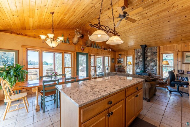 118 Sunset Rd, Ely, MN 55731 - kitchen with vaulted ceiling, open floor plan, a wood stove, wood walls, and light tile patterned flooring