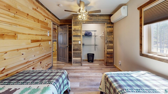 7498 Bayside Dr, Crane Lake, MN 55725 - bedroom featuring an AC wall unit, wood walls, wood finished floors, a ceiling fan, and a closet