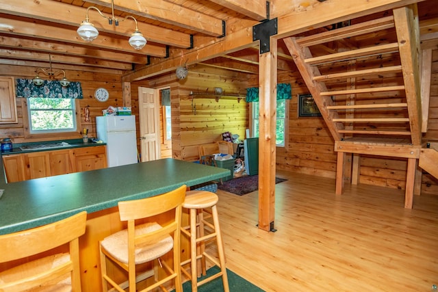 1808 Tom Lake Rd, Hovland, MN 55606 - kitchen with freestanding refrigerator, light wood-type flooring, wood walls, beamed ceiling, and a breakfast bar