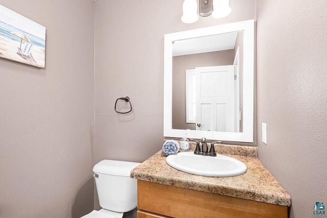half bath featuring vanity and toilet
