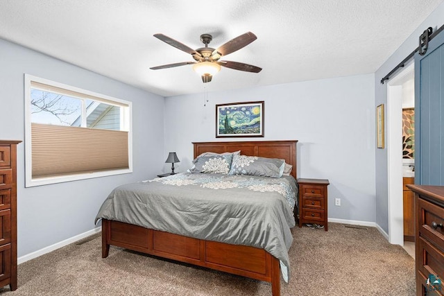 carpeted bedroom featuring a barn door, baseboards, and ceiling fan