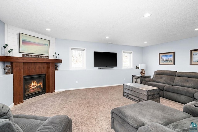 carpeted living area with a textured ceiling, recessed lighting, a large fireplace, and baseboards