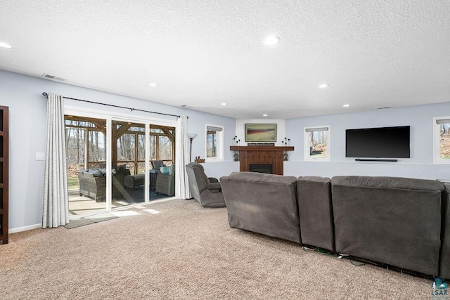 carpeted living area featuring a textured ceiling, recessed lighting, and a fireplace