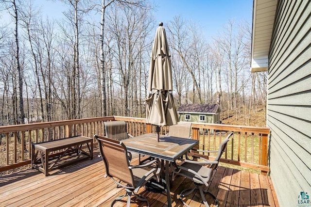 wooden terrace with outdoor dining space and an outdoor structure