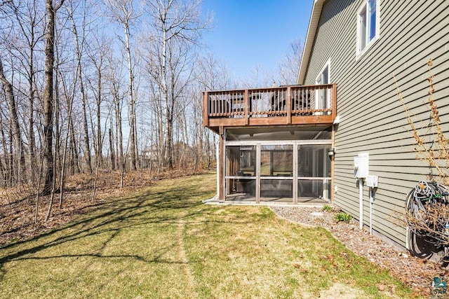 view of green lawn featuring a sunroom and a wooden deck