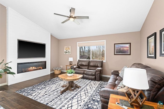 living area featuring vaulted ceiling, ceiling fan, baseboards, wood finished floors, and a fireplace