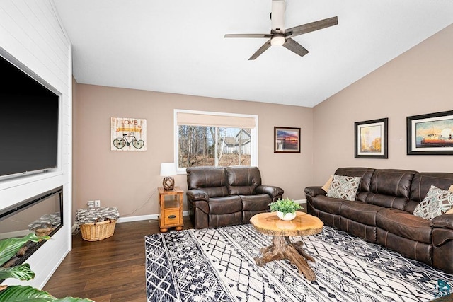 living area featuring dark wood finished floors, baseboards, ceiling fan, and vaulted ceiling