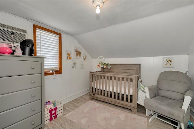 121 11th St, Cloquet, MN 55720 - bedroom featuring wood finished floors, vaulted ceiling, a nursery area, baseboards, and a wall mounted air conditioner