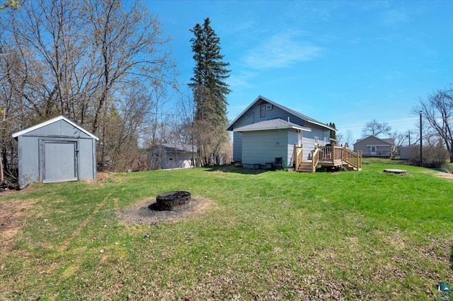 121 11th St, Cloquet, MN 55720 - view of green lawn featuring a fire pit, a wooden deck, a shed, and an outbuilding
