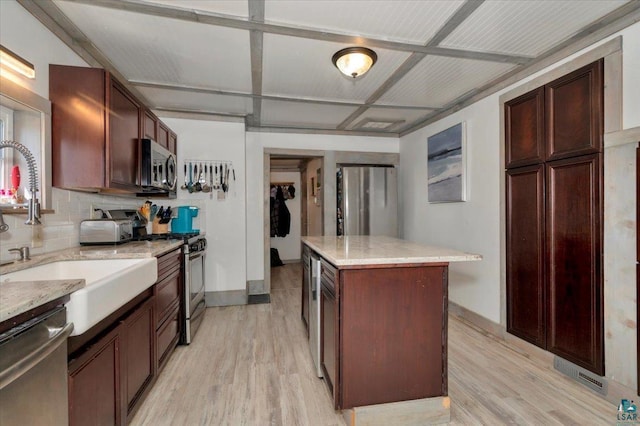 121 11th St, Cloquet, MN 55720 - kitchen featuring stainless steel appliances, light wood-style floors, a kitchen island, light stone countertops, and a sink