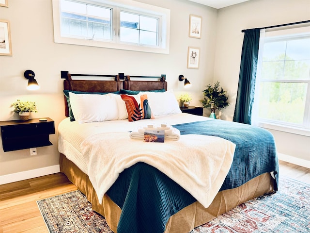 bedroom with baseboards, multiple windows, and wood finished floors