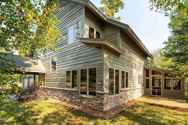 879 Clearwater Rd, Grand Marais, MN 55604 - rear view of house with a sunroom, stone siding, and a lawn