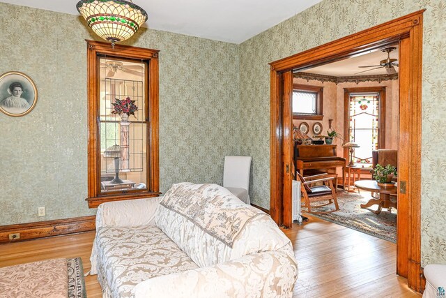 living area featuring wood-type flooring, radiator heating unit, wallpapered walls, and ceiling fan