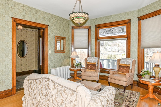 living room featuring radiator heating unit, hardwood / wood-style floors, baseboards, and wallpapered walls