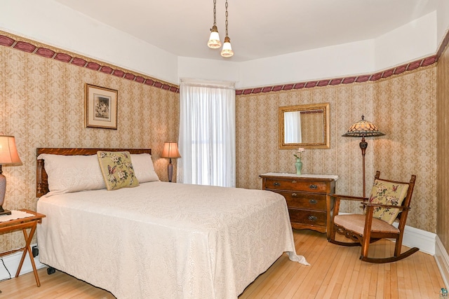 bedroom with light wood-style floors and wallpapered walls
