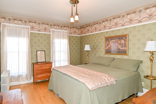 bedroom featuring light wood-style floors, multiple windows, and wallpapered walls