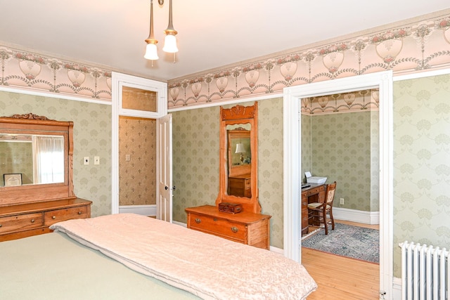 bedroom featuring radiator heating unit and light wood-style flooring