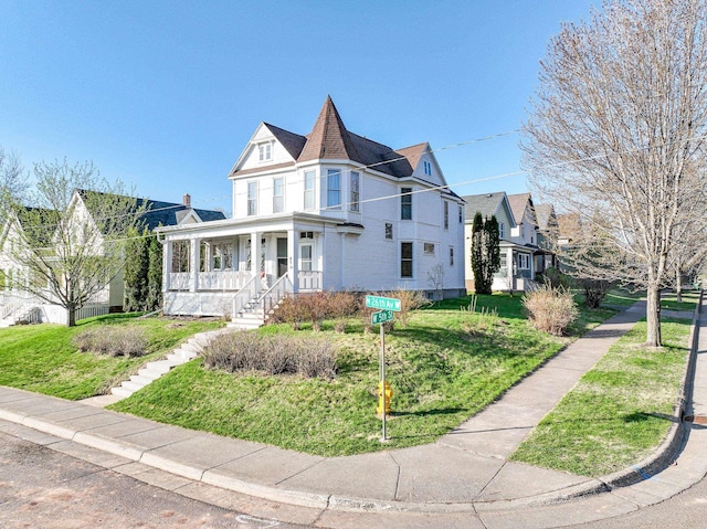 victorian house featuring covered porch and a front yard
