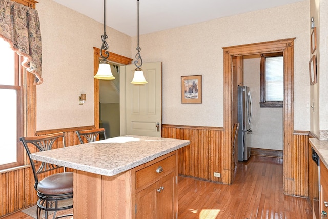 kitchen featuring appliances with stainless steel finishes, brown cabinetry, light wood-style floors, light countertops, and plenty of natural light