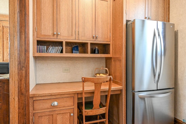 kitchen featuring freestanding refrigerator, light countertops, open shelves, and brown cabinetry