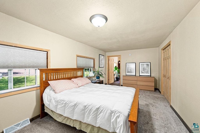 bedroom with light carpet, a textured ceiling, and a textured wall