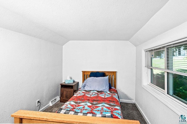 carpeted bedroom with lofted ceiling, a textured ceiling, baseboards, and a textured wall