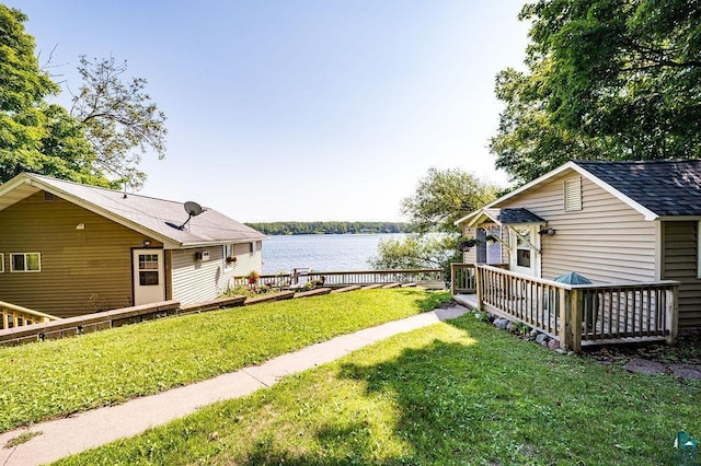 view of grassy yard featuring a deck with water view