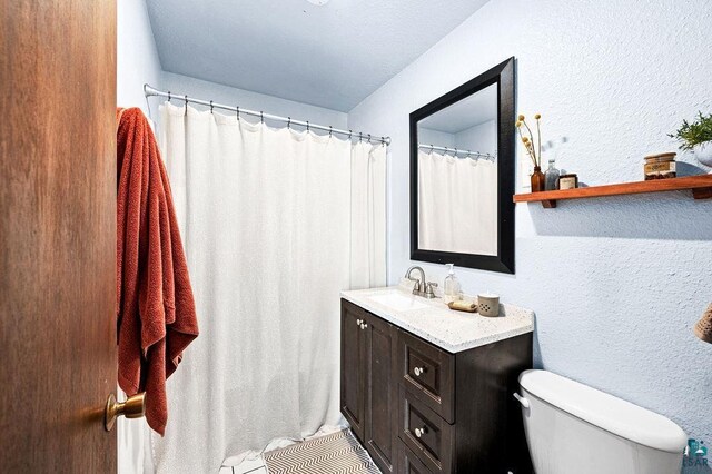 bathroom with vanity, a textured wall, and toilet