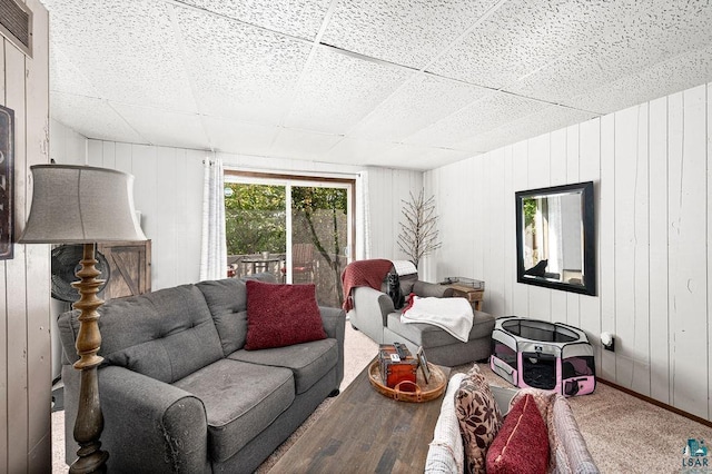carpeted living area with a paneled ceiling