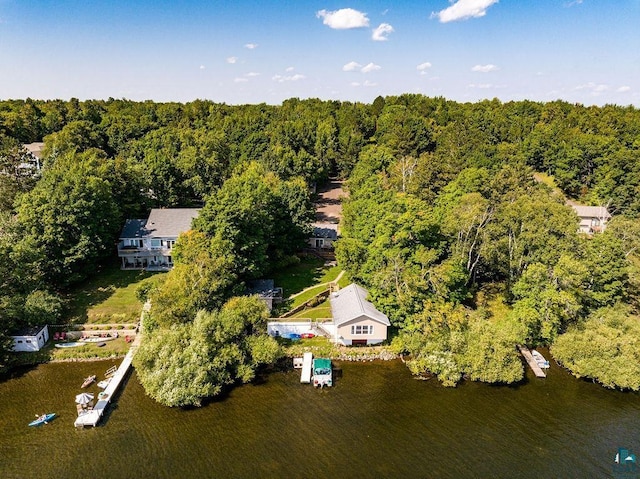 aerial view of property and surrounding area with a heavily wooded area and a large body of water