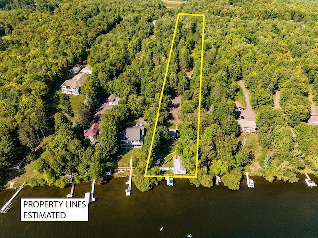aerial view of property and surrounding area featuring a heavily wooded area, property boundaries highlighted, and a nearby body of water