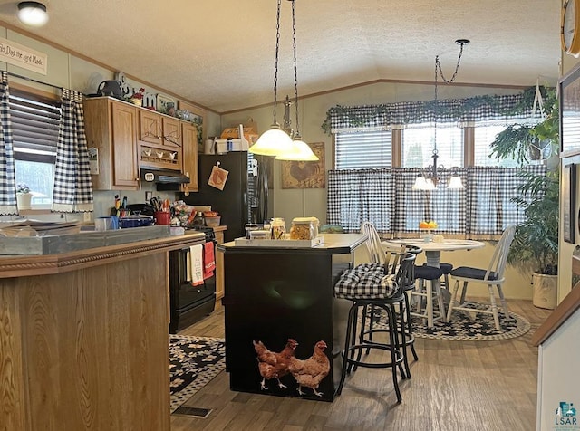 kitchen featuring lofted ceiling, a chandelier, light wood-type flooring, brown cabinetry, and a textured ceiling
