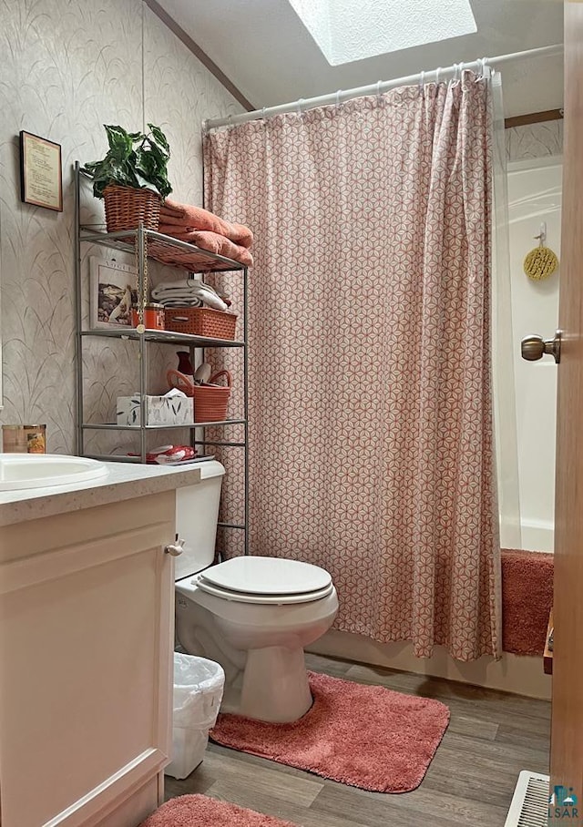 full bathroom with wallpapered walls, wood finished floors, toilet, vanity, and curtained shower