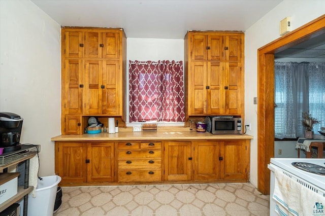 304 Carlton Ave, Cloquet, MN 55720 - kitchen with brown cabinets, stainless steel microwave, light floors, light countertops, and electric range
