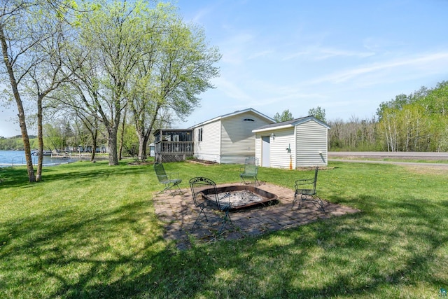 10412 Lakeside Dr, Finlayson, MN 55735 - view of green lawn featuring a fire pit, an outbuilding, a deck with water view, and a storage shed