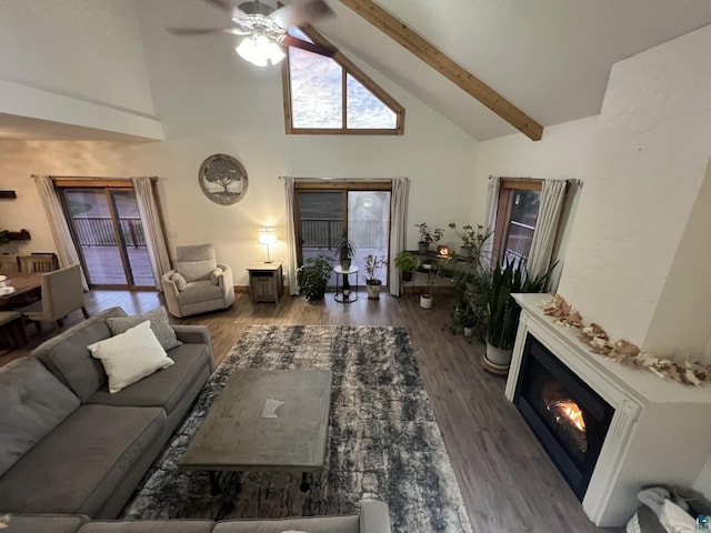 7789 Jokela Rd, Cloquet, MN 55720 - living area with high vaulted ceiling, a ceiling fan, beamed ceiling, wood finished floors, and a glass covered fireplace
