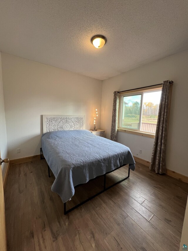 7789 Jokela Rd, Cloquet, MN 55720 - bedroom with hardwood / wood-style floors, a textured ceiling, and baseboards