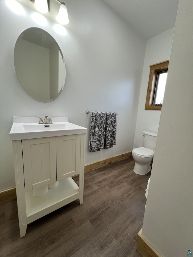 7789 Jokela Rd, Cloquet, MN 55720 - half bathroom featuring toilet, wood finished floors, vanity, and baseboards