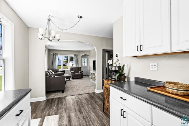 426 22nd St, Cloquet, MN 55720 - kitchen featuring arched walkways, dark wood-style flooring, dark countertops, baseboards, and white cabinetry