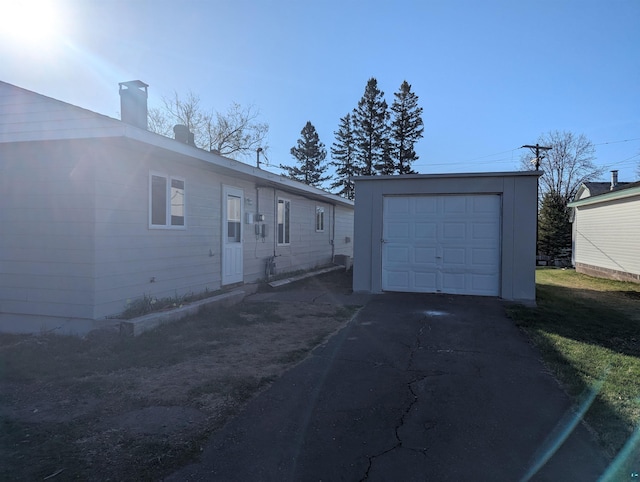 81 Edison Blvd, Silver Bay, MN 55614 - view of front of property with an outbuilding, a garage, asphalt driveway, and a chimney