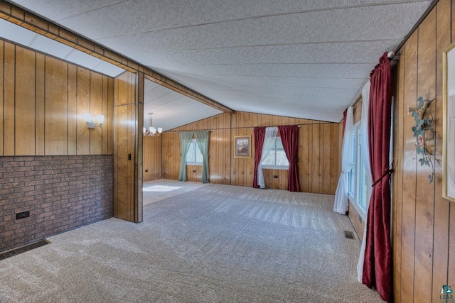4538 Bass Lake Rd, Gilbert, MN 55741 - empty room featuring wood walls, carpet floors, a chandelier, brick wall, and lofted ceiling