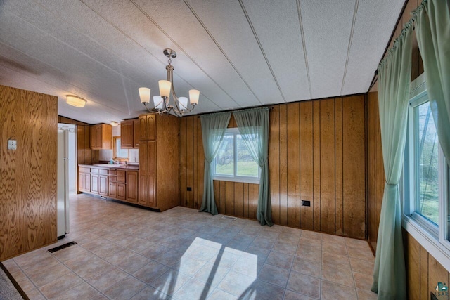 4538 Bass Lake Rd, Gilbert, MN 55741 - kitchen with brown cabinets, wood walls, a chandelier, a sink, and a textured ceiling