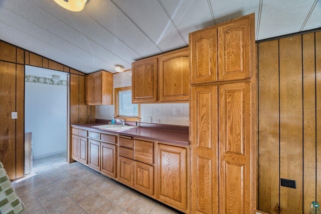 4538 Bass Lake Rd, Gilbert, MN 55741 - kitchen featuring wooden walls, brown cabinets, a sink, lofted ceiling, and a textured ceiling