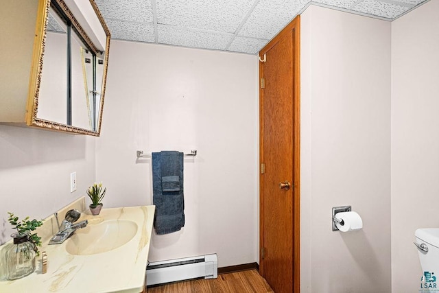3026 Getchell Rd, Duluth, MN 55810 - bathroom featuring baseboard heating, a paneled ceiling, toilet, wood finished floors, and baseboards