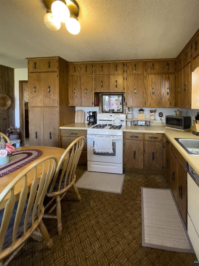 110 Hays Crk, Silver Bay, MN 55614 - kitchen with white appliances, brown cabinetry, light countertops, a textured ceiling, and a sink