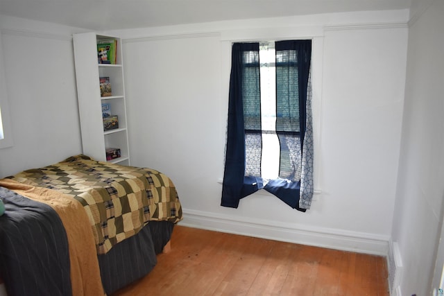 bedroom with wood-type flooring and baseboards